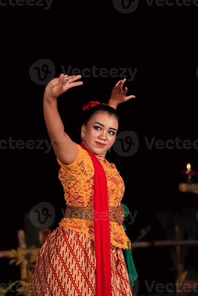 balinesische frau im traditionellen orangefarbenen kleid, das mit einem roten schal tanzt, während es tanzt foto