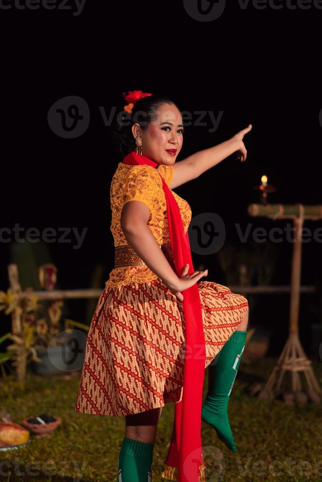 asiatische frau, die einen traditionellen tanz namens jaipong in indonesien mit einem gelben kleid und einem roten schal aufführt foto