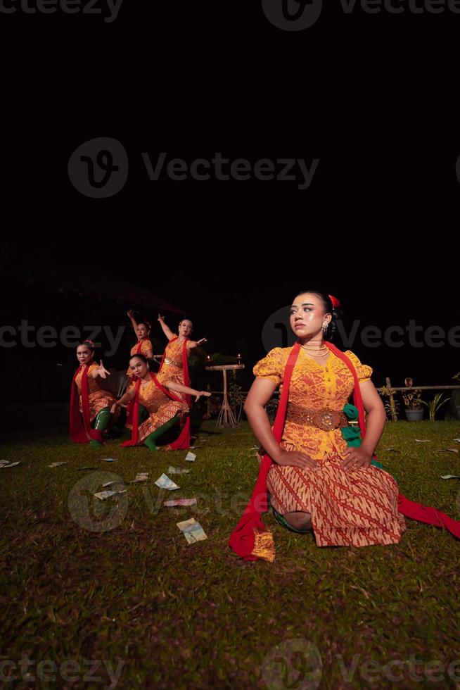 eine gruppe indonesischer tänzer, die auf der bühne mit einem roten schal und einem traditionellen orangefarbenen kleid innerhalb des festivals auftreten foto