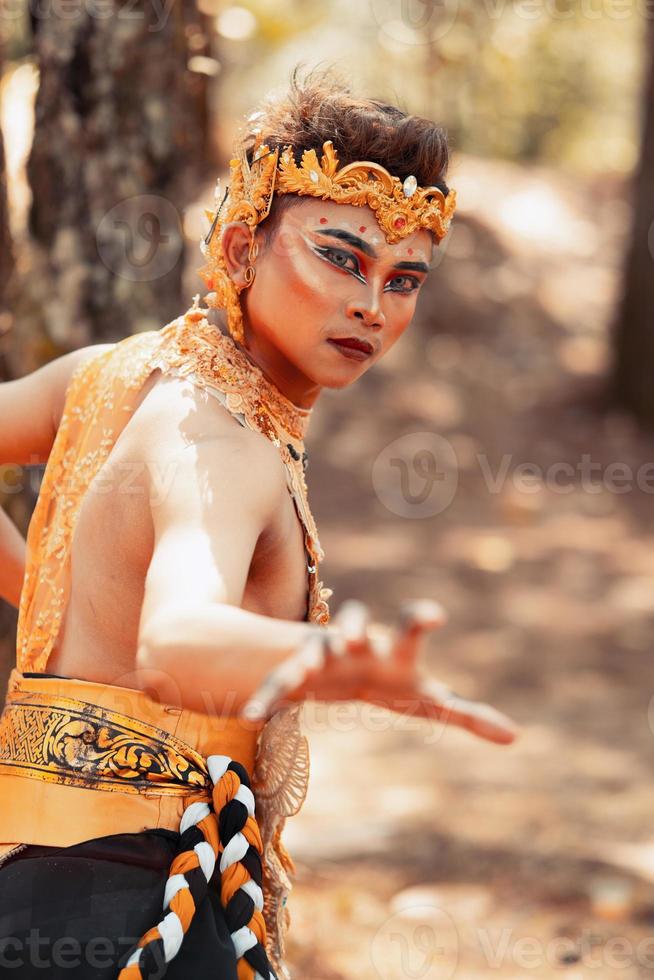 männlicher asiatischer mann, der in einer goldenen krone und in goldenen kleidern aufwirft, während er make-up trägt foto