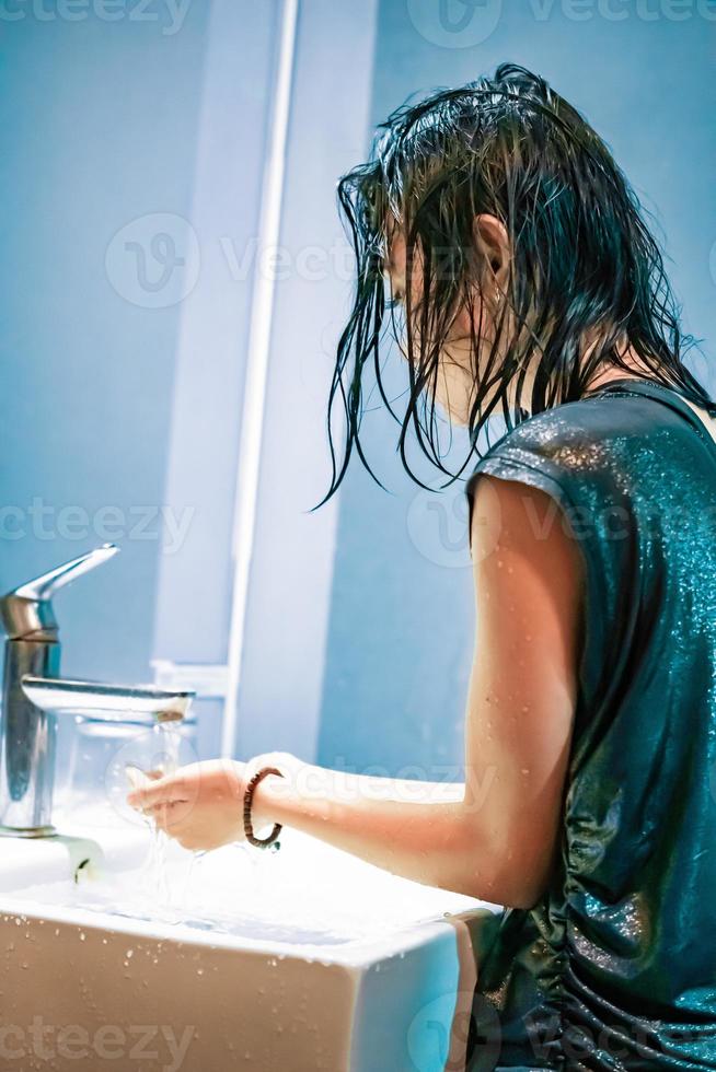 eine junge frau wäscht ihre hände im weißen waschbecken vor dem virus covid-19 foto