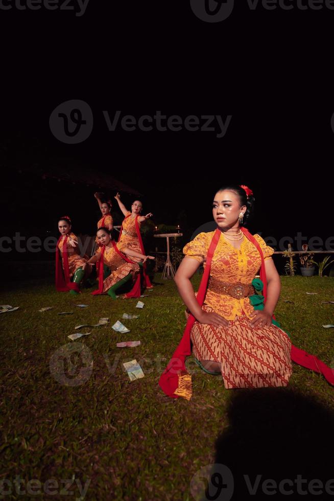 eine gruppe indonesischer tänzer, die auf der bühne mit einem roten schal und einem traditionellen orangefarbenen kleid innerhalb des festivals auftreten foto