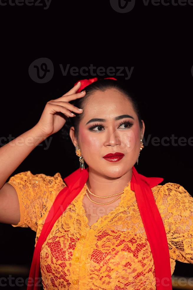 exotische indonesische frauen mit roten lippen und make-up, während sie ein orangefarbenes kleid und einen roten schal tragen foto