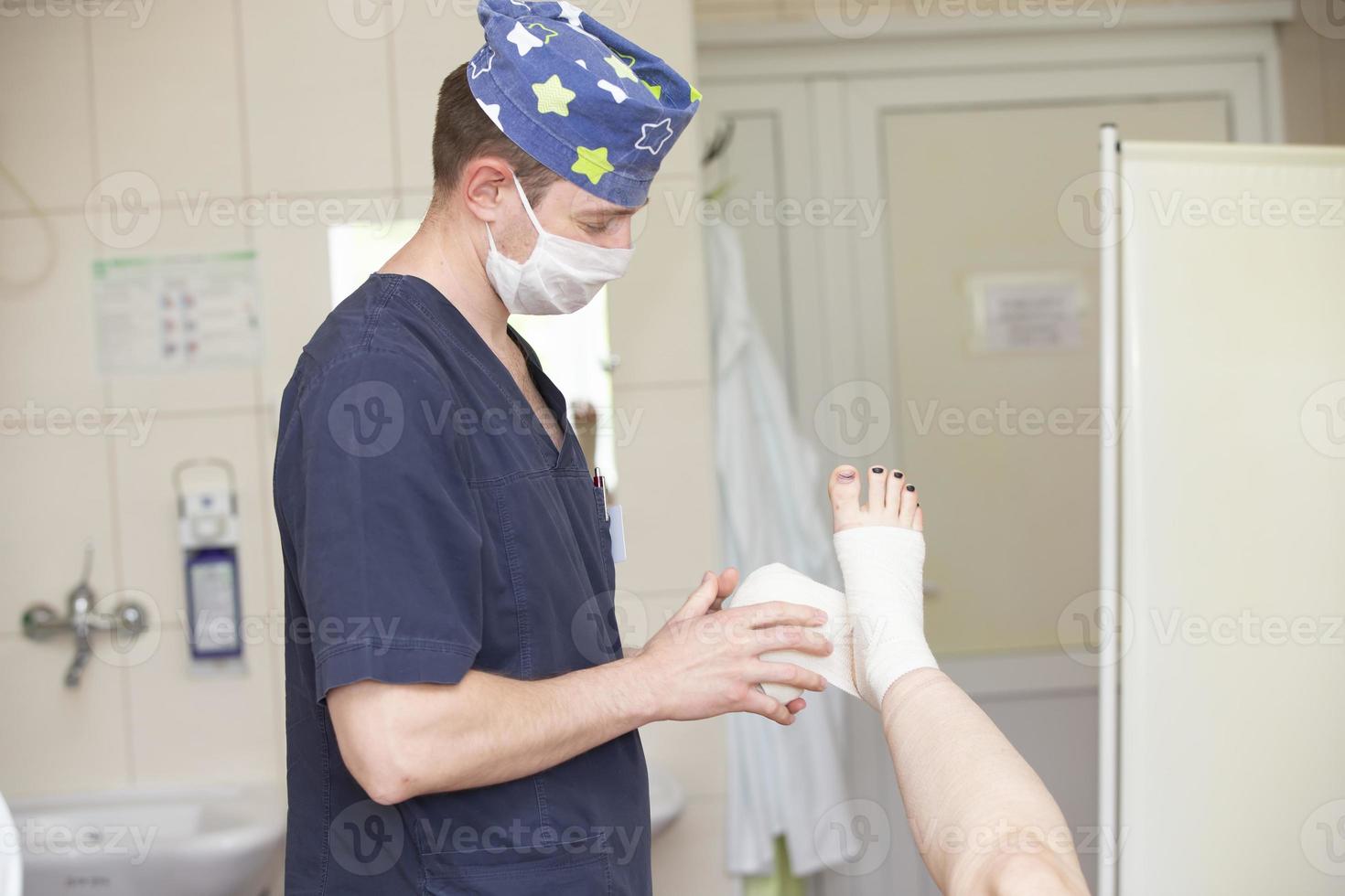 Der Arzt verbindet das Bein des Patienten. Chirurg und Patient nach einer Venenoperation. foto