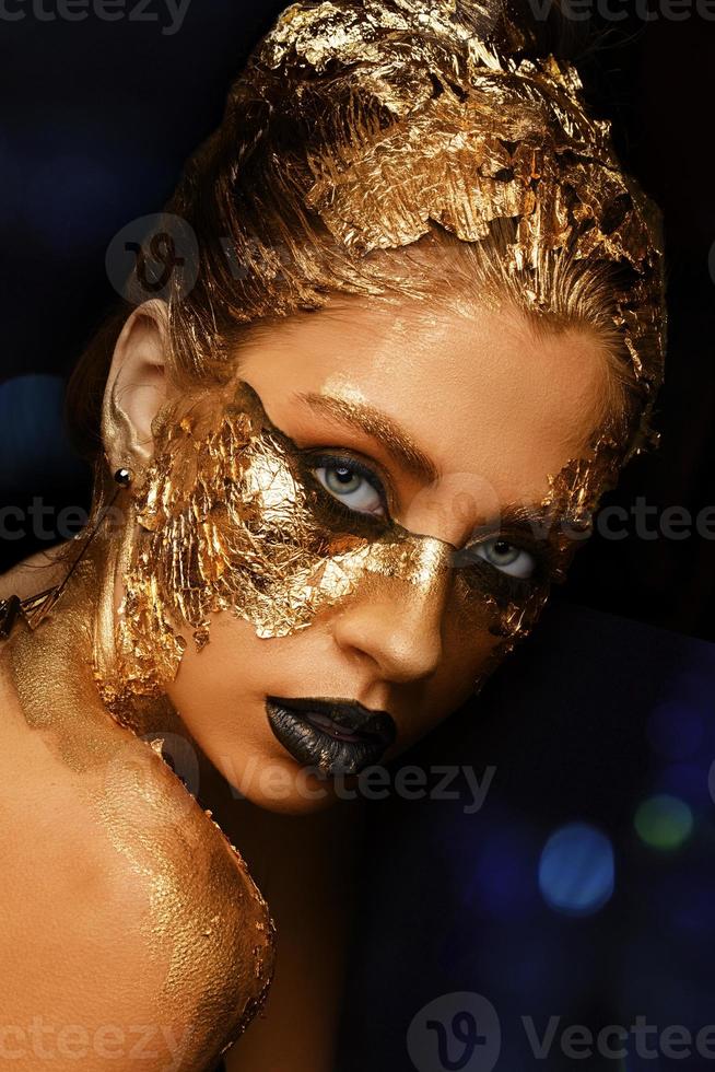 Modekunst goldene Haut. vorbildliches mädchen mit festlichem goldenem glamourösem glänzendem professionellem make-up. Goldschmuck, Bijouterie, Accessoires. schöner goldener metallischer Körper, schwarze Lippen und Haut. foto