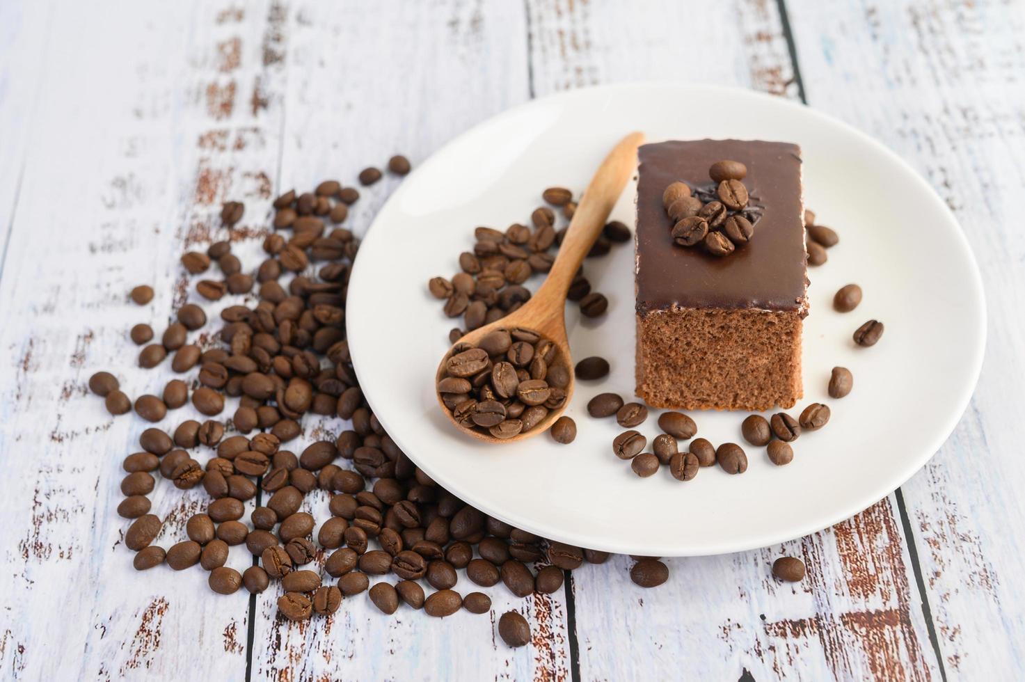 Schokoladenkuchen auf einem weißen Teller und Kaffeebohnen foto