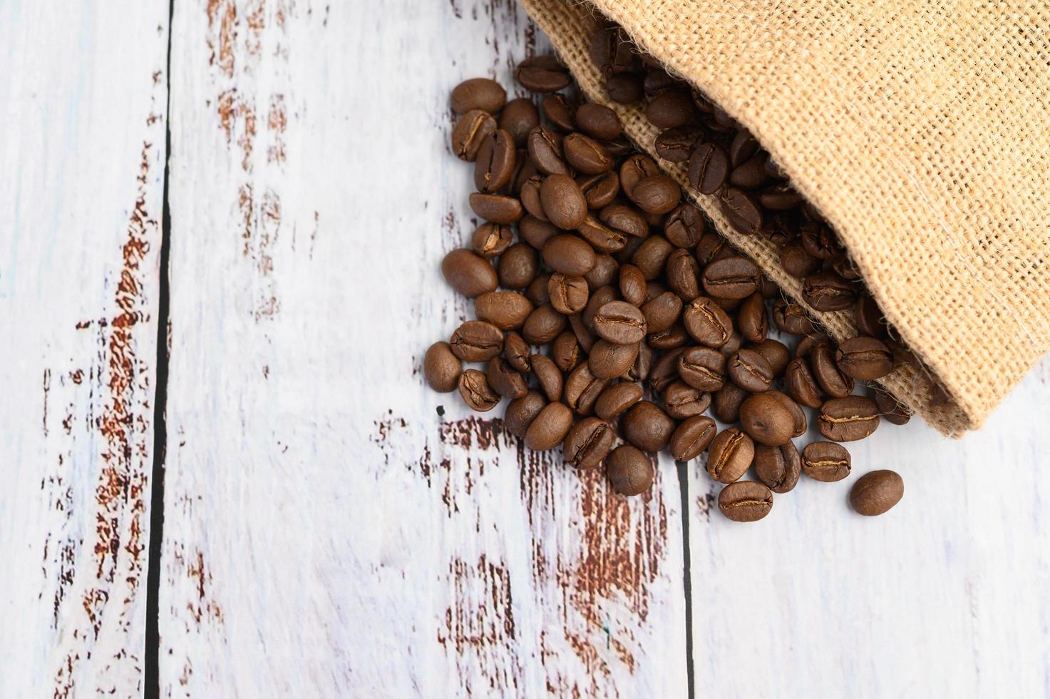 Kaffeebohnen in Hanfsäcken auf einem weißen Holztisch foto