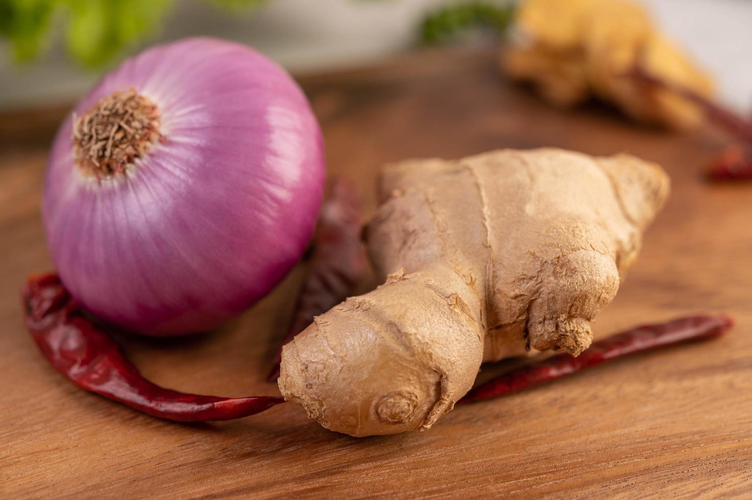 rote Zwiebel, Pfeffer und Ingwer auf einem Holztisch foto