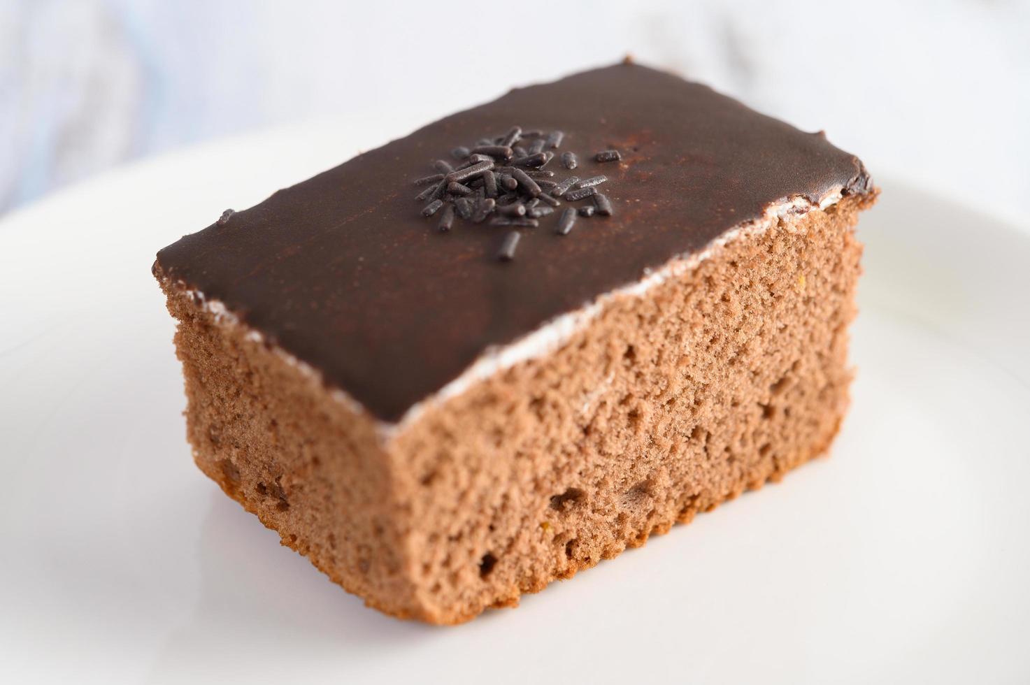 Schokoladenkuchen auf einem weißen Teller und einem weißen Holztisch foto