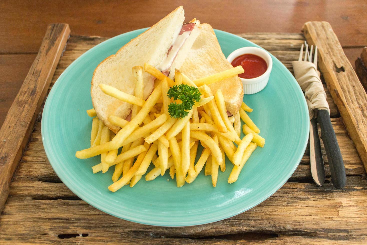 Schinken-Käse-Sandwich mit Pommes Frites auf blauem Teller foto