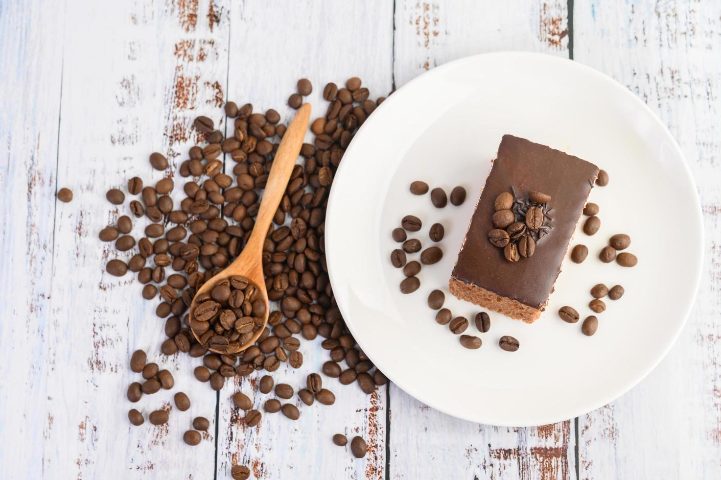 Schokoladenkuchen auf einem weißen Teller und Kaffeebohnen foto