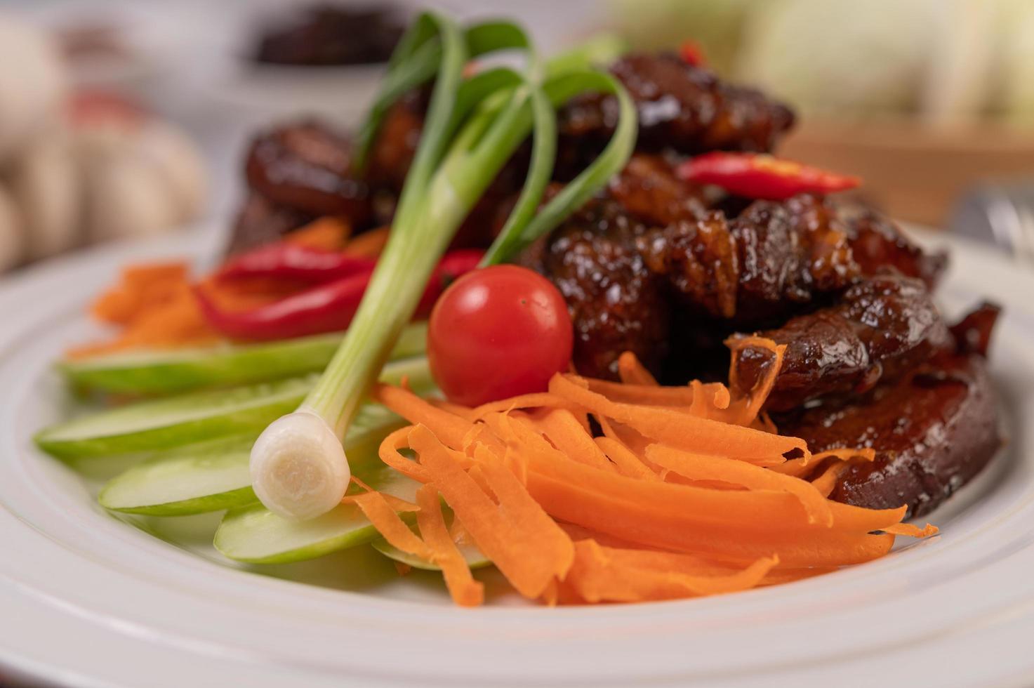 süßes Schweinefleisch mit Paprika, Frühlingszwiebeln, Karotten und Tomaten foto