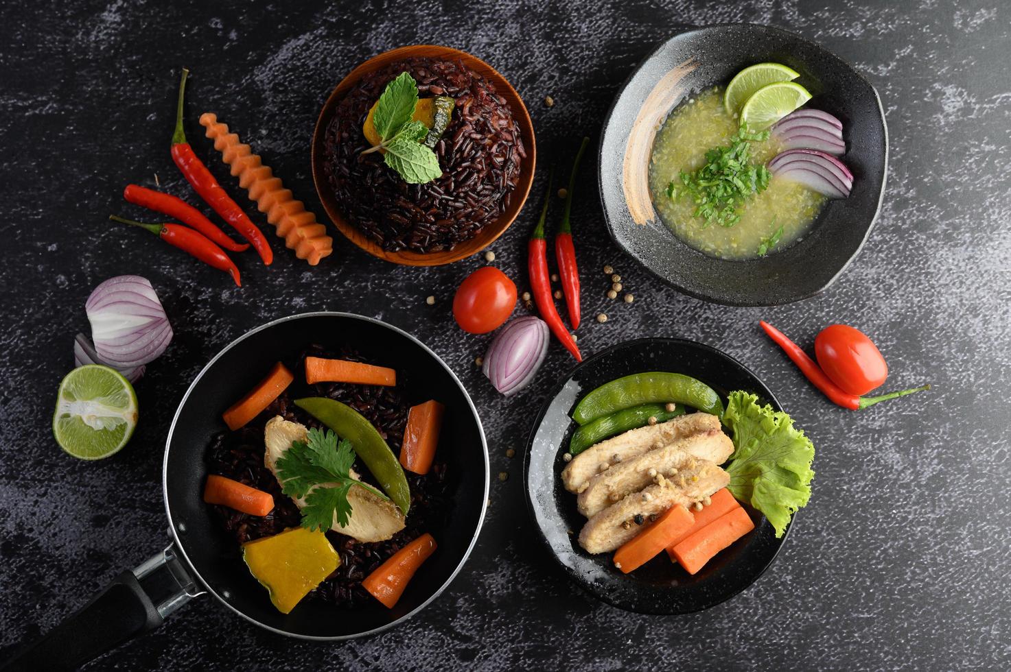 verschiedene Gerichte von Gemüse, Fleisch und Fisch auf einem schwarzen Steinhintergrund foto