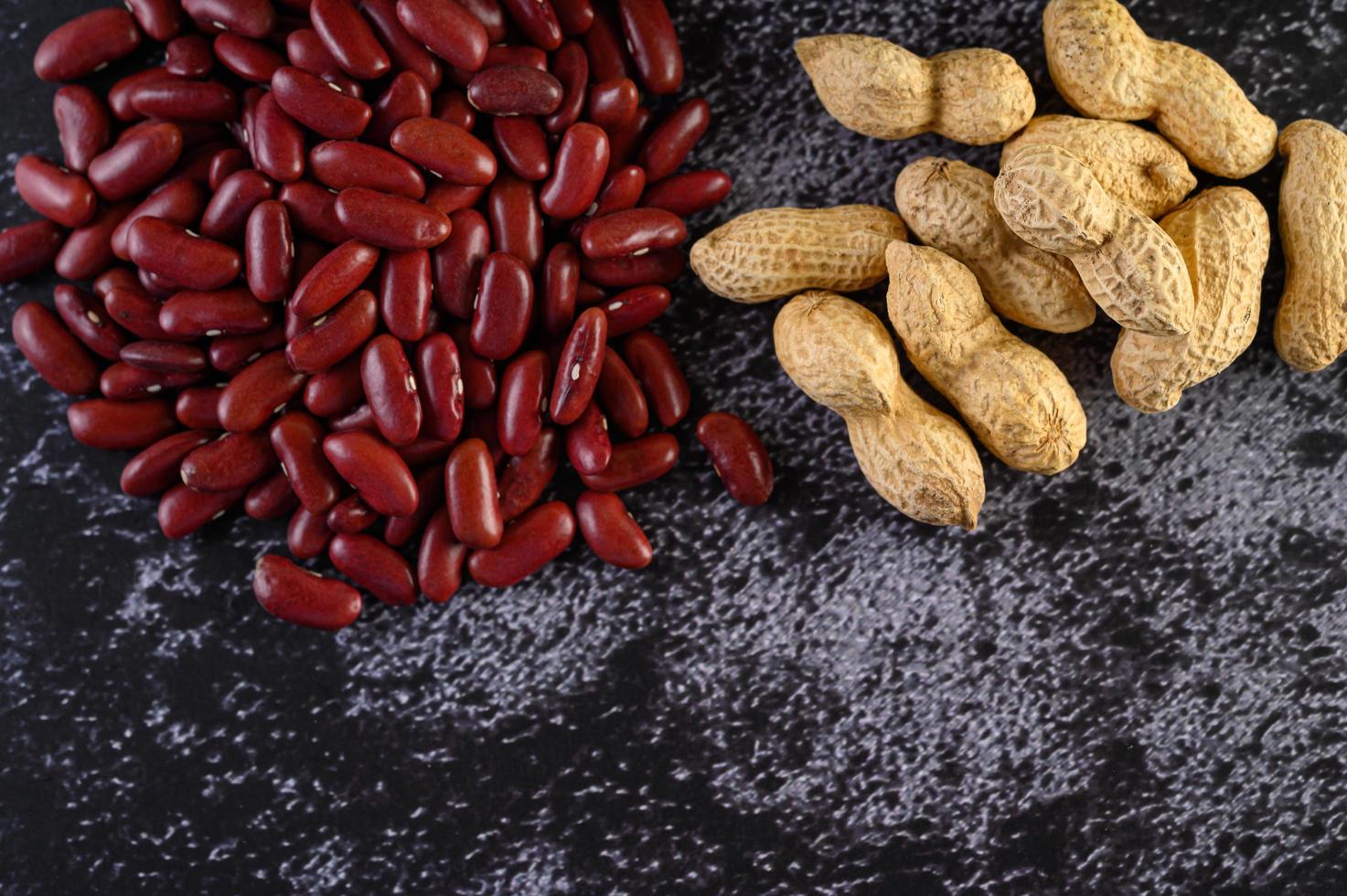 Erdnüsse und rote Bohnen auf einem schwarzen Zementbodenhintergrund foto