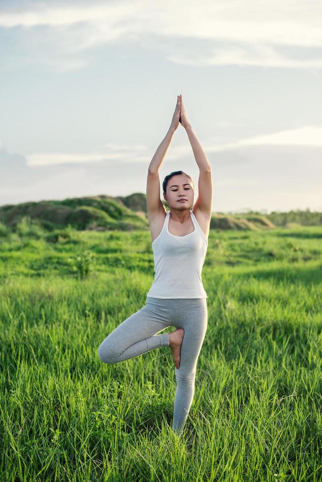 junge schöne Frau, die Yoga in den Wiesen praktiziert foto