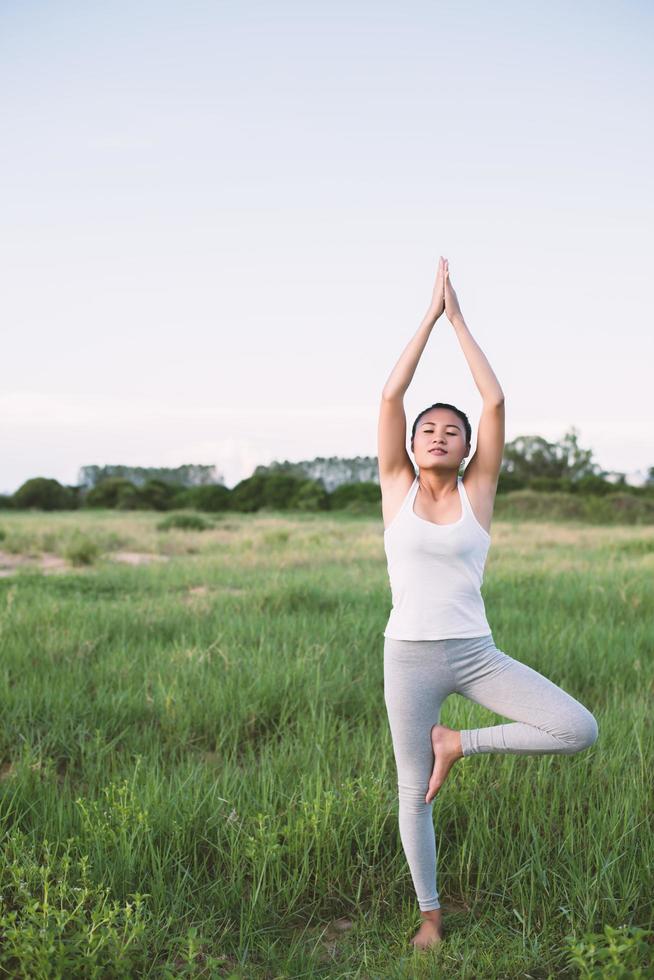 junge schöne Frau, die Yoga in den Wiesen praktiziert foto