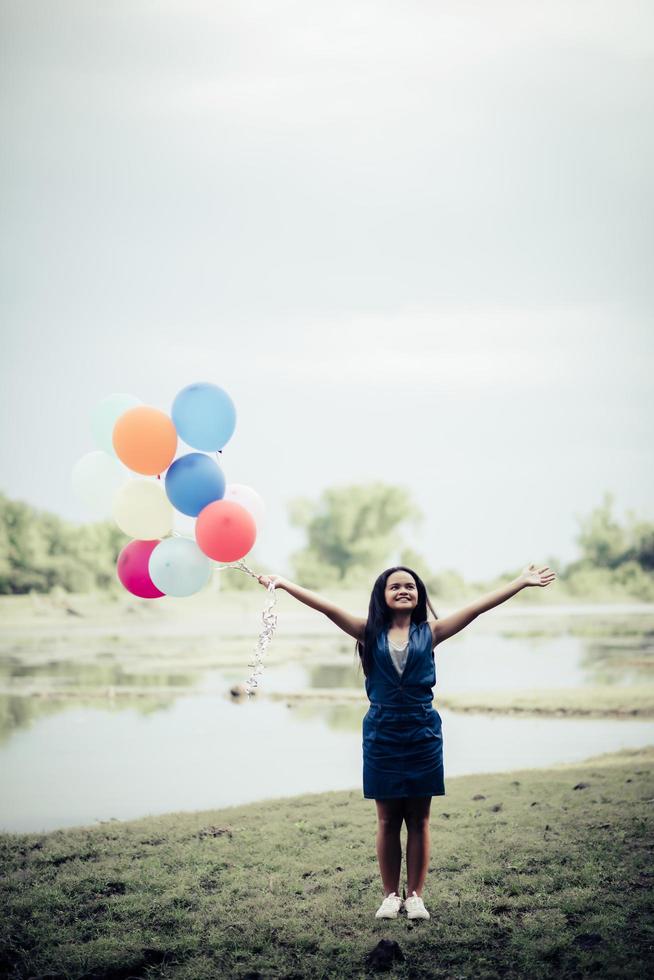 junge Frau, die bunte Luftballons in der Natur hält foto