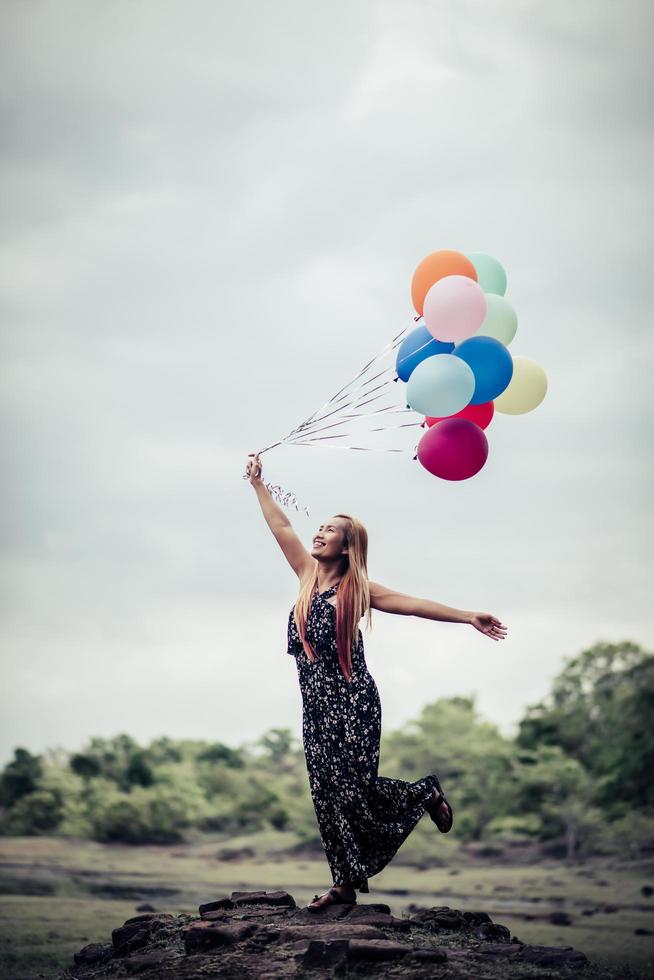 junge Frau, die bunte Luftballons in der Natur hält foto