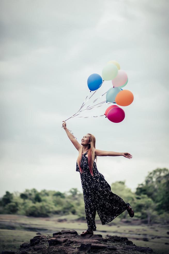 junge Frau, die bunte Luftballons in der Natur hält foto