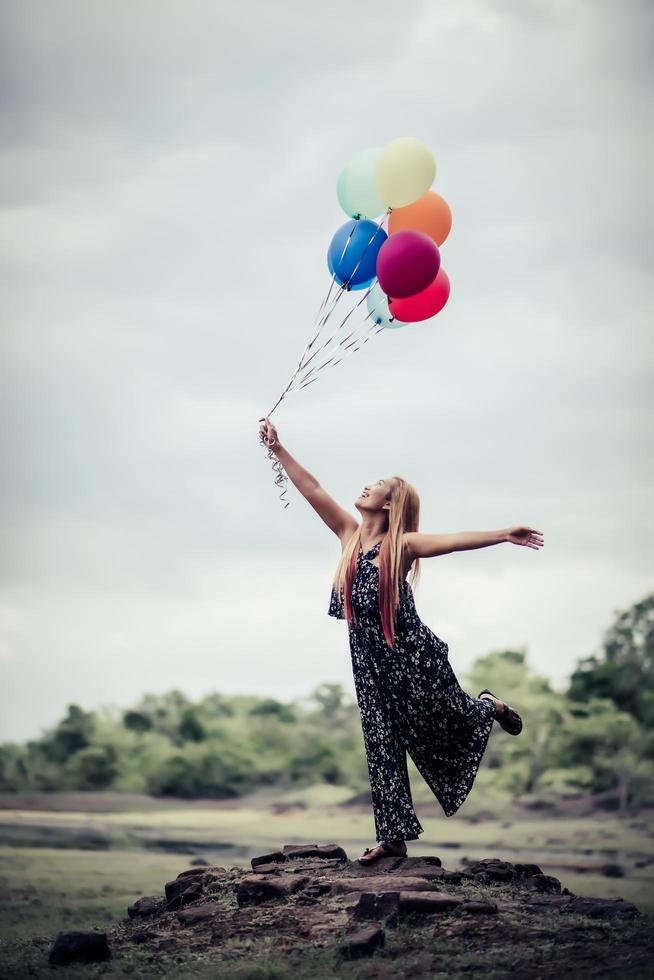 junge Frau, die bunte Luftballons in der Natur hält foto