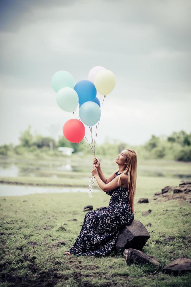 junge Frau, die bunte Luftballons in der Natur hält foto