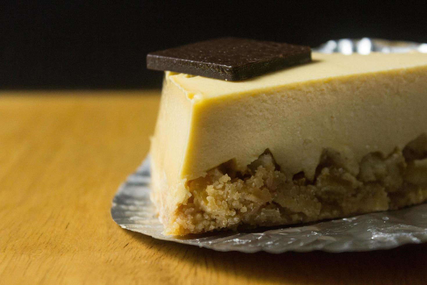 Nahaufnahme der Scheibe Käsekuchen auf Holztisch und dunklem Hintergrund foto