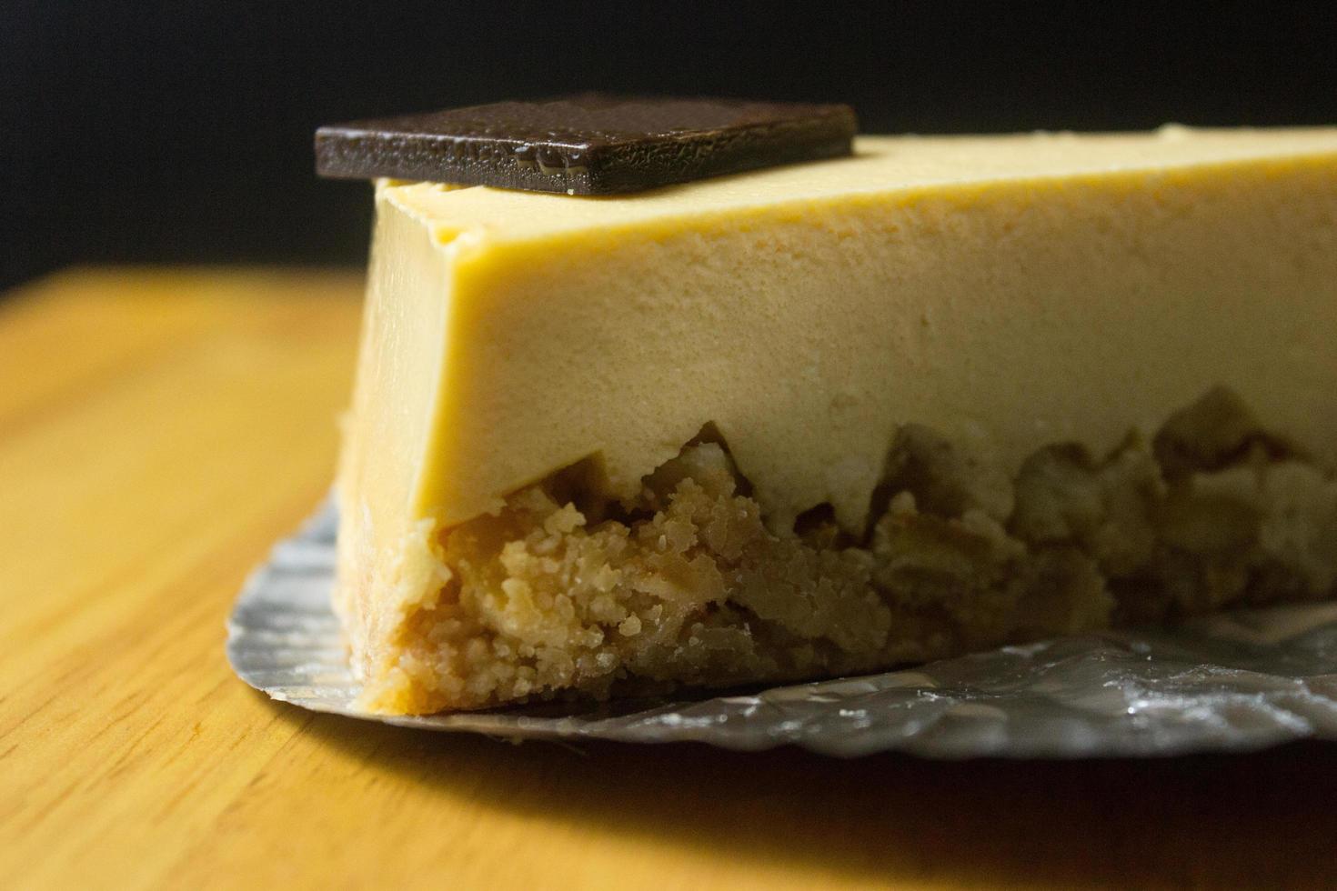 Nahaufnahme der Scheibe Käsekuchen auf Holztisch und dunklem Hintergrund foto