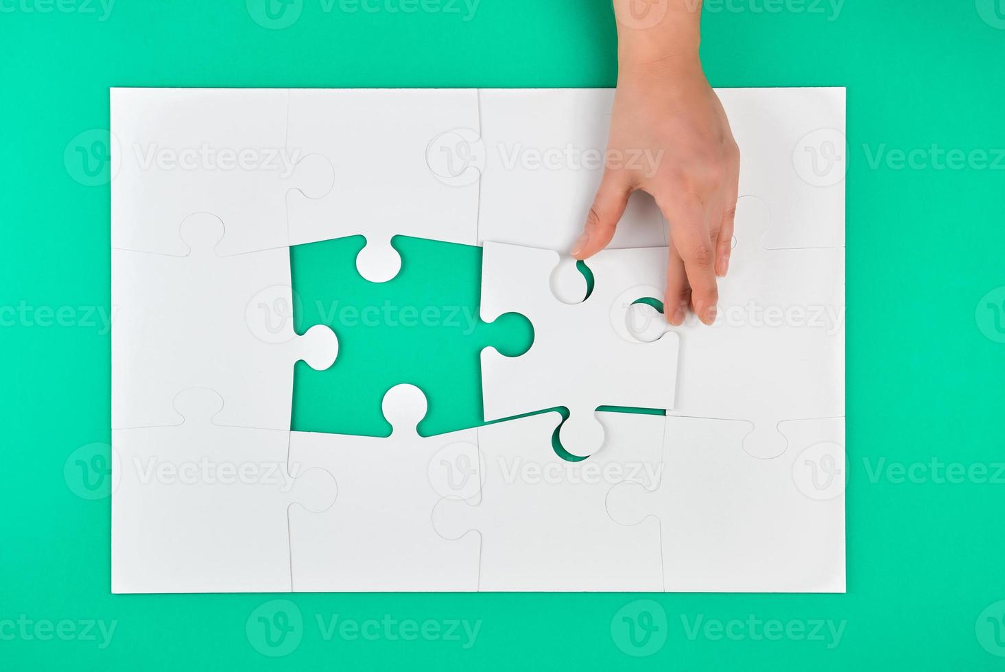 Hand hält das fehlende Element im Puzzlespiel auf grünem Hintergrund foto