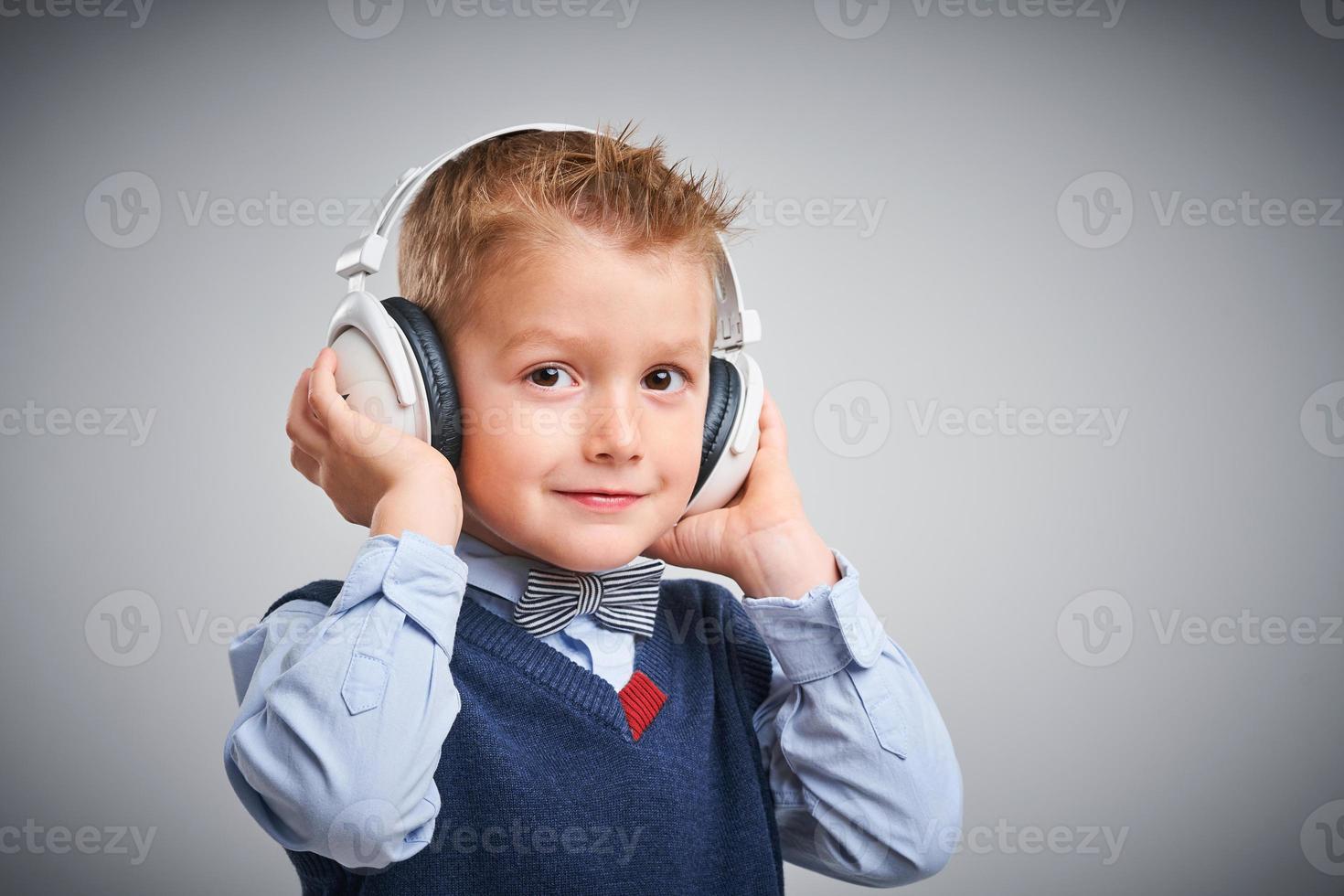Porträt eines 4-jährigen Jungen, der über Weiß mit Kopfhörern posiert foto