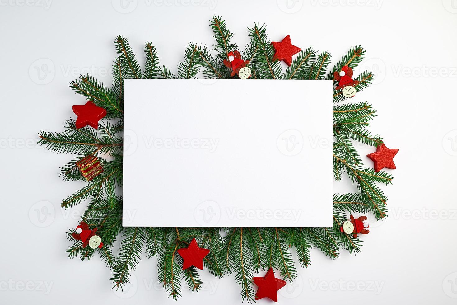 Glückwunschweihnachtshintergrund mit einem leeren weißen Blatt und grünen Fichtenzweigen foto