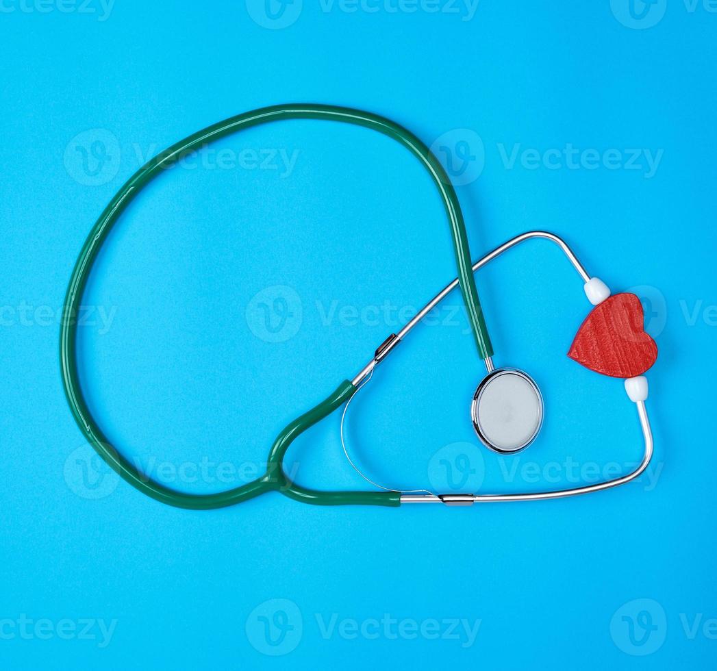 grünes medizinisches stethoskop und rotes holzherz foto