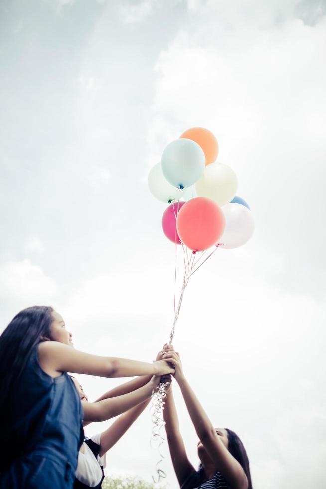 glückliche Gruppenfreundinnen, die bunte Luftballons an einem Park halten foto