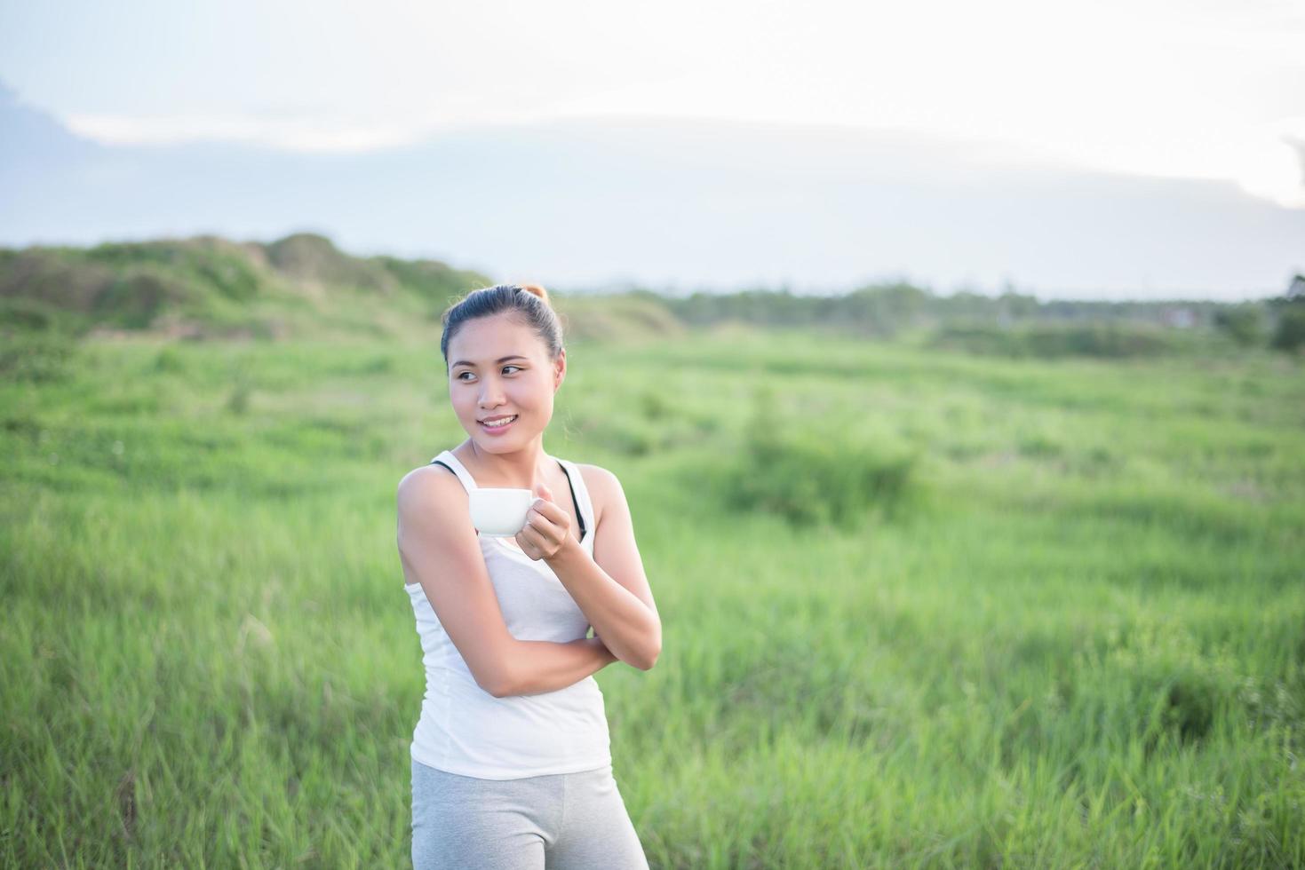 schöne asiatische Frau, die Kaffee in einer Wiese trinkt foto