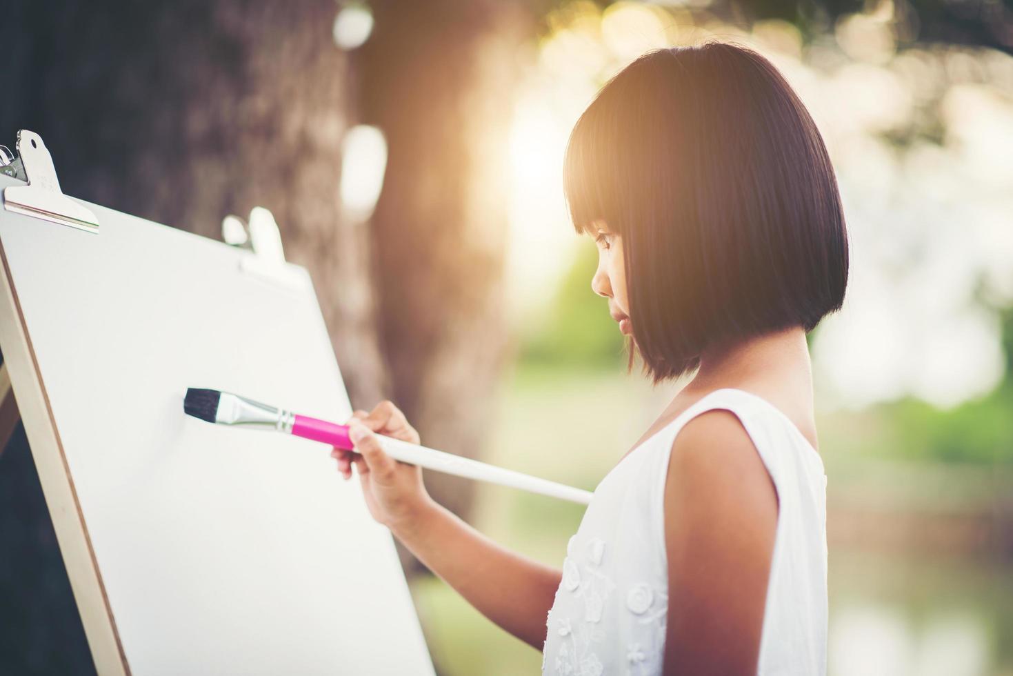 Künstlerin des kleinen Mädchens, die ein Bild im Park malt foto