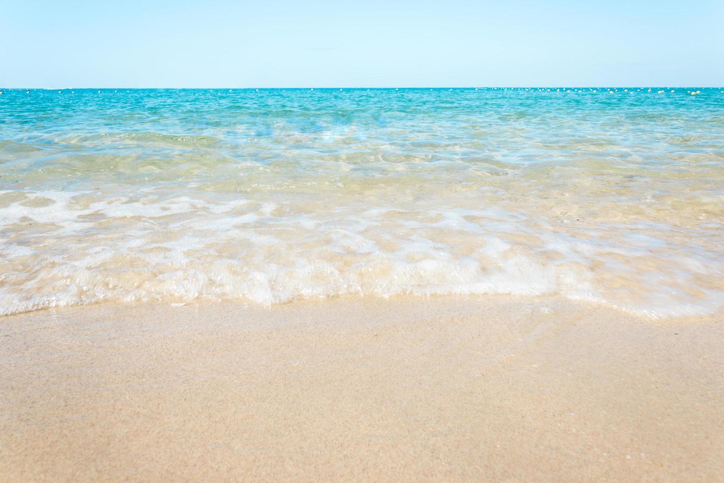 Ozeanwellen auf Sandstrand mit klarem blauem Himmel foto