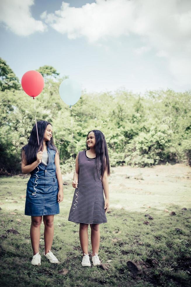 glückliche Gruppenfreundinnen, die bunte Luftballons an einem Park halten foto