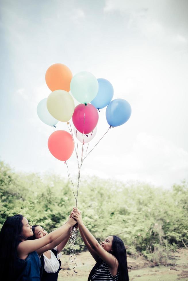 glückliche Gruppenfreundinnen, die bunte Luftballons an einem Park halten foto