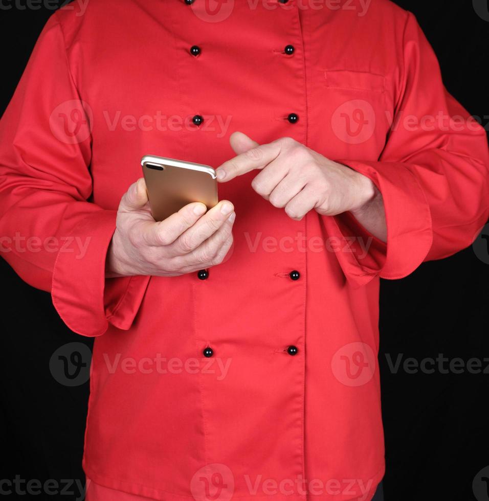 Koch in roter Uniform hält ein Smartphone in der Hand foto