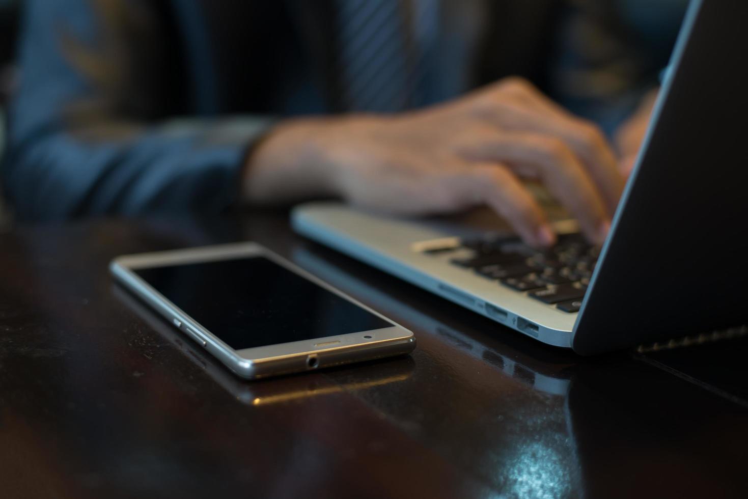 Hände des Geschäftsmannes, die auf einer Laptoptastatur am Arbeitsplatz tippen foto