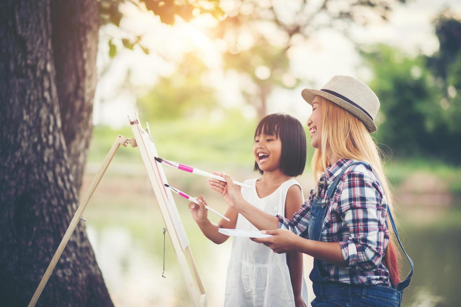 Mutter und Töchter malen gemeinsam Bilder in einem Park foto