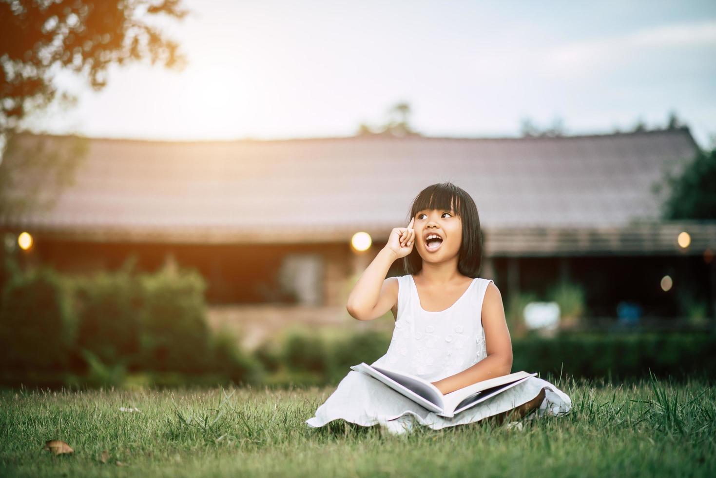 kleines Mädchen liest ein Buch in ihrem Hausgarten draußen foto