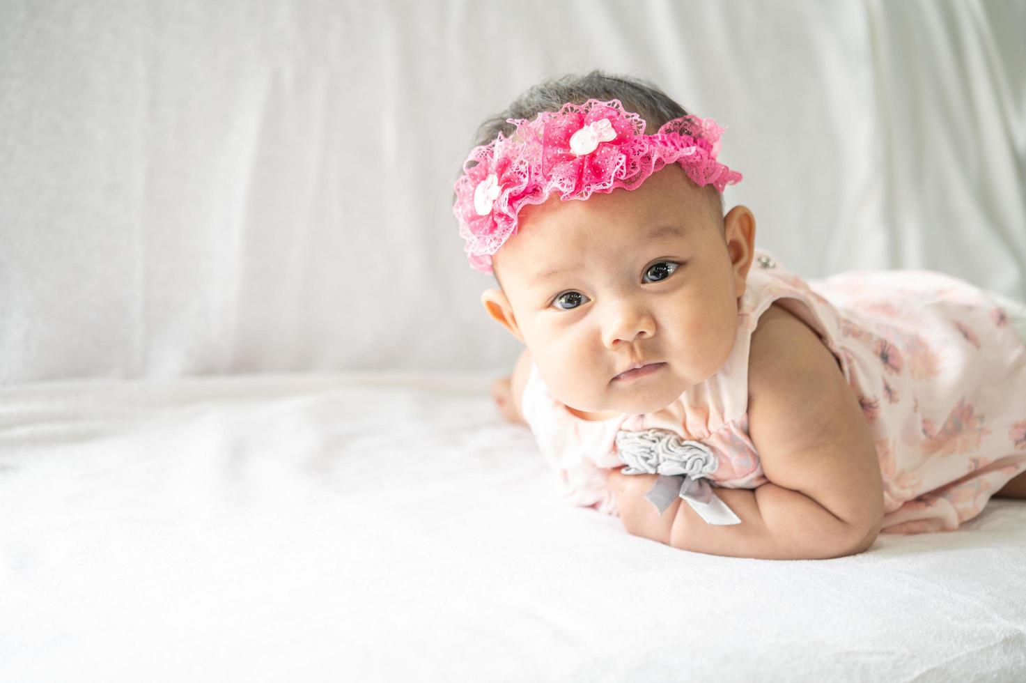 Das Baby liegt mit dem Kopf nach oben auf dem Bett foto