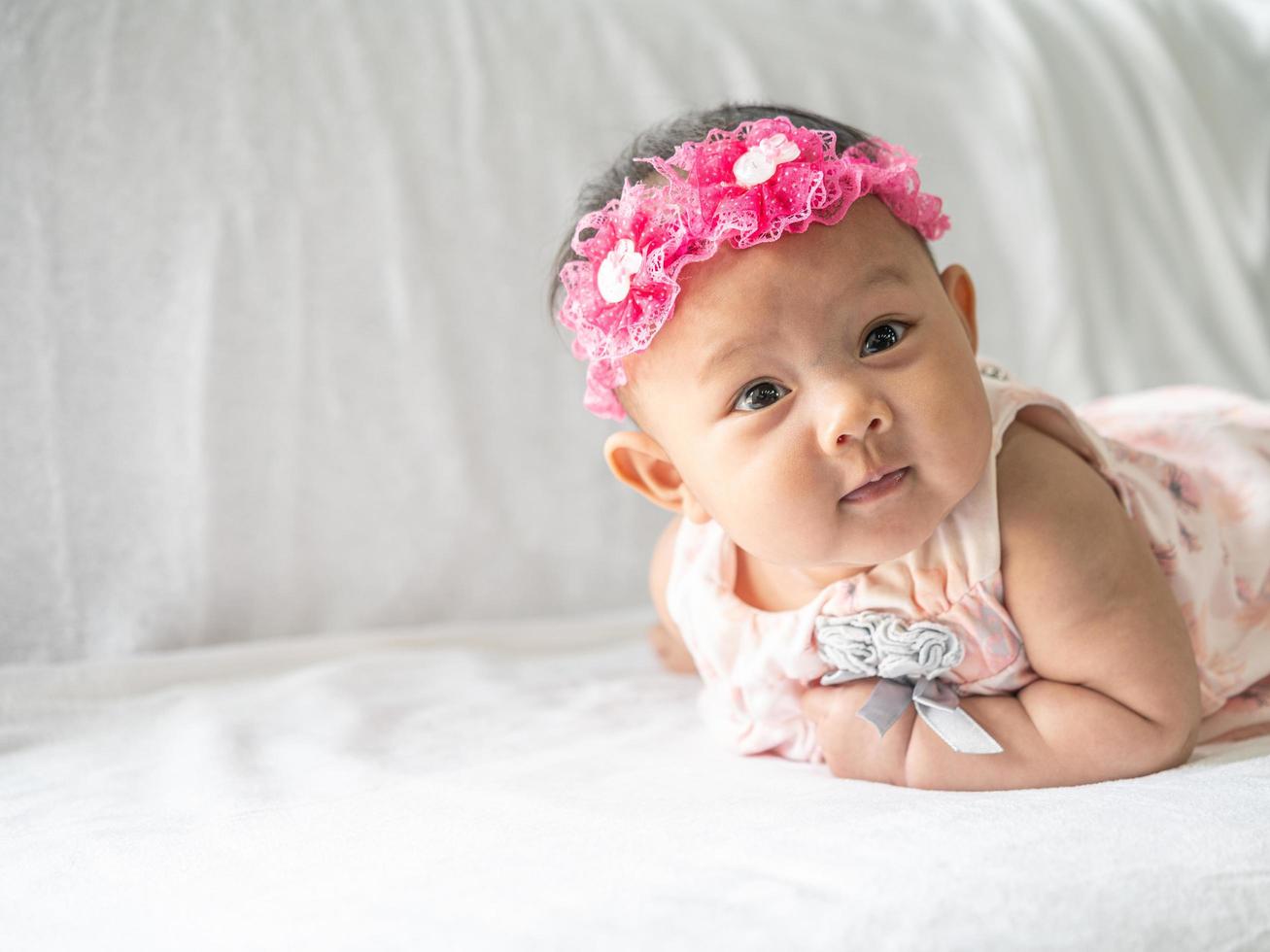 Das Baby liegt mit dem Kopf nach oben auf dem Bett foto