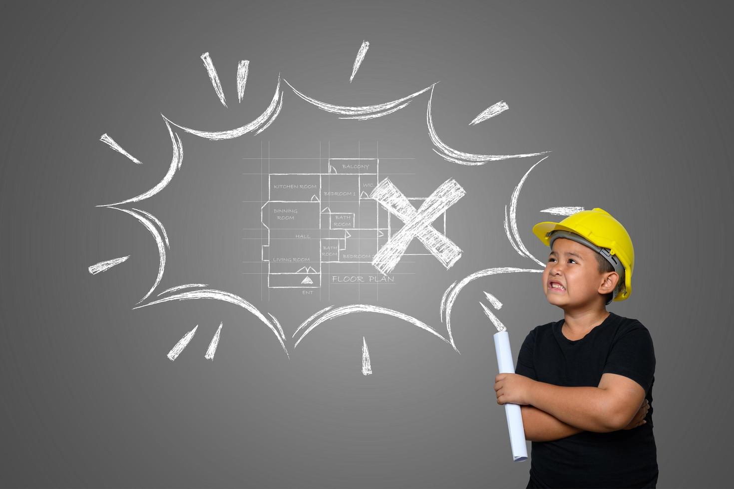 Ein Junge trägt einen gelben Ingenieurhut und einen Hausplan an der Tafel foto
