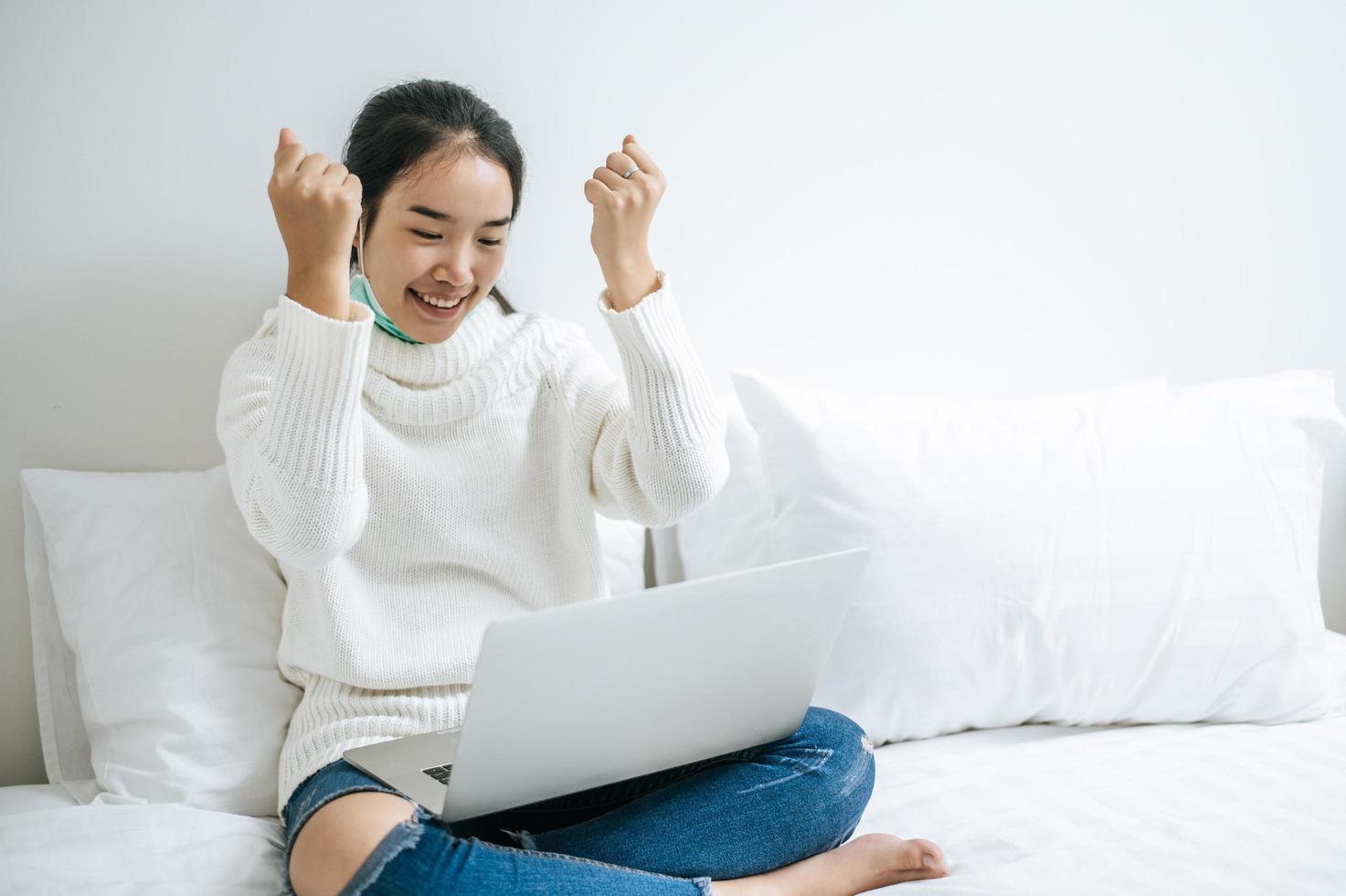 junge Frau, die ein weißes Hemd trägt, das auf ihrem Laptop spielt foto