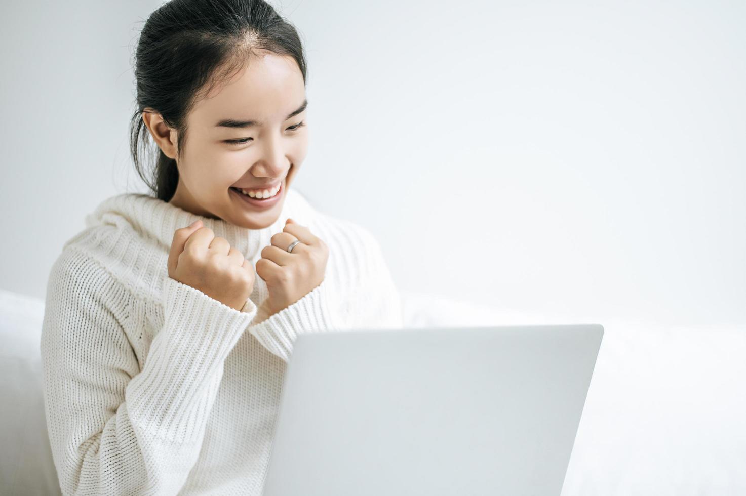 junge Frau, die ein weißes Hemd trägt, das auf ihrem Laptop spielt foto