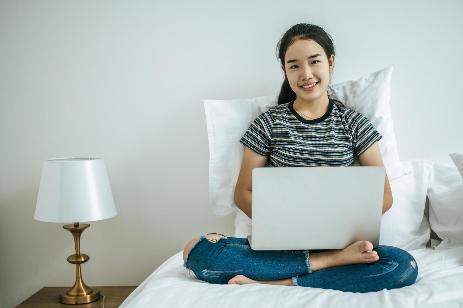 eine junge Frau spielt auf ihrem Laptop im Bett foto