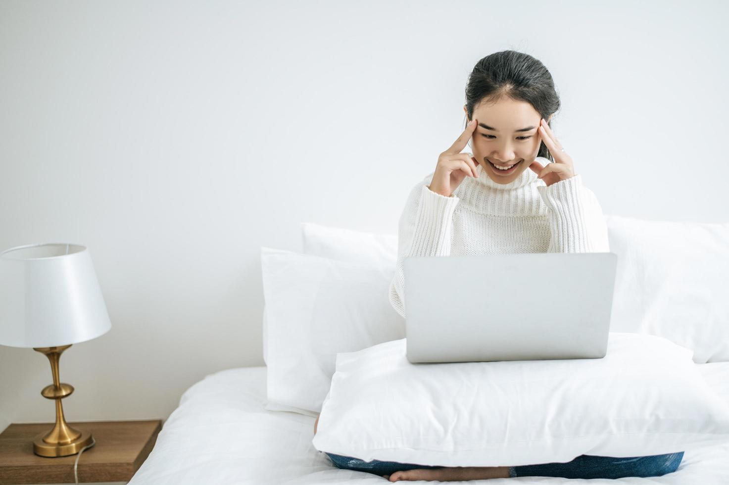 junge Frau, die ein weißes Hemd trägt, das auf ihrem Laptop spielt foto