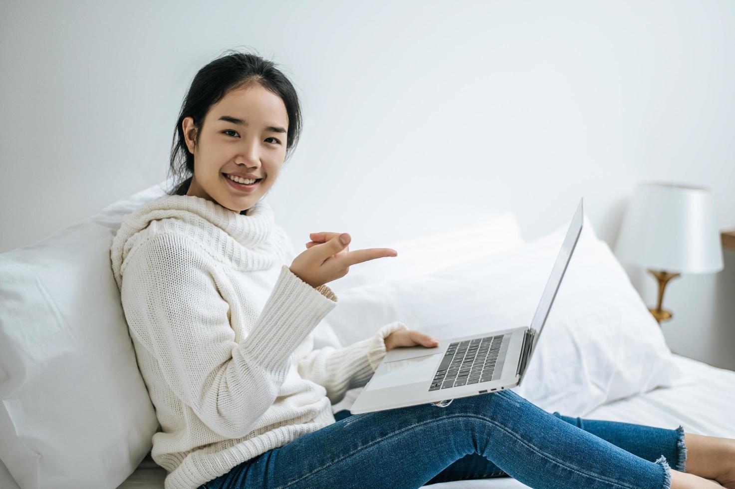 junge Frau, die ein weißes Hemd trägt, das auf ihrem Laptop spielt foto