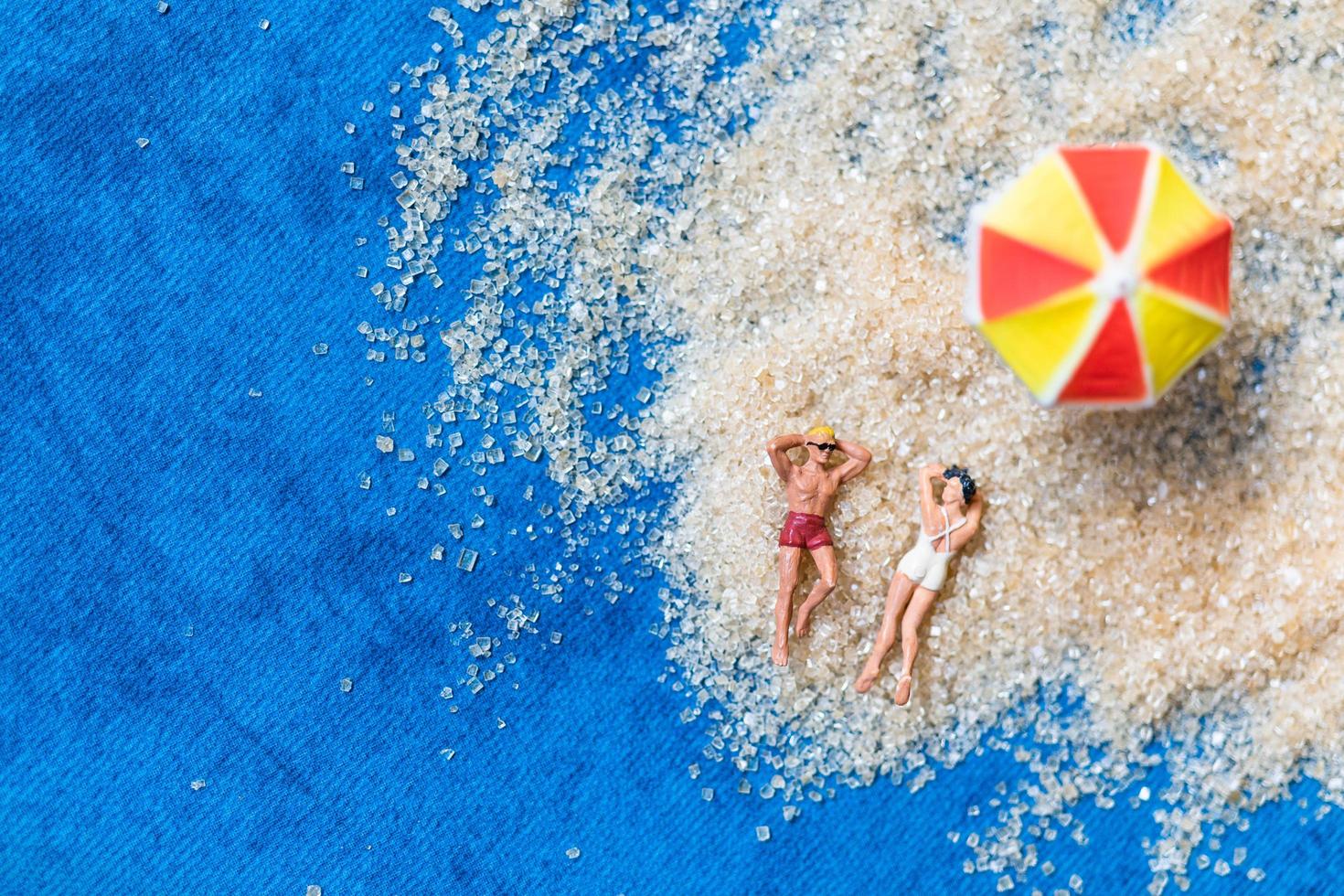 Miniaturfiguren sitzen am Strand foto